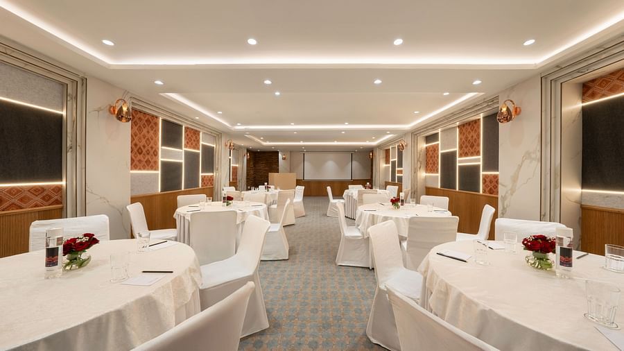 A spacious conference room with round tables and chairs set up for a meeting - Clarks Inn, Indore