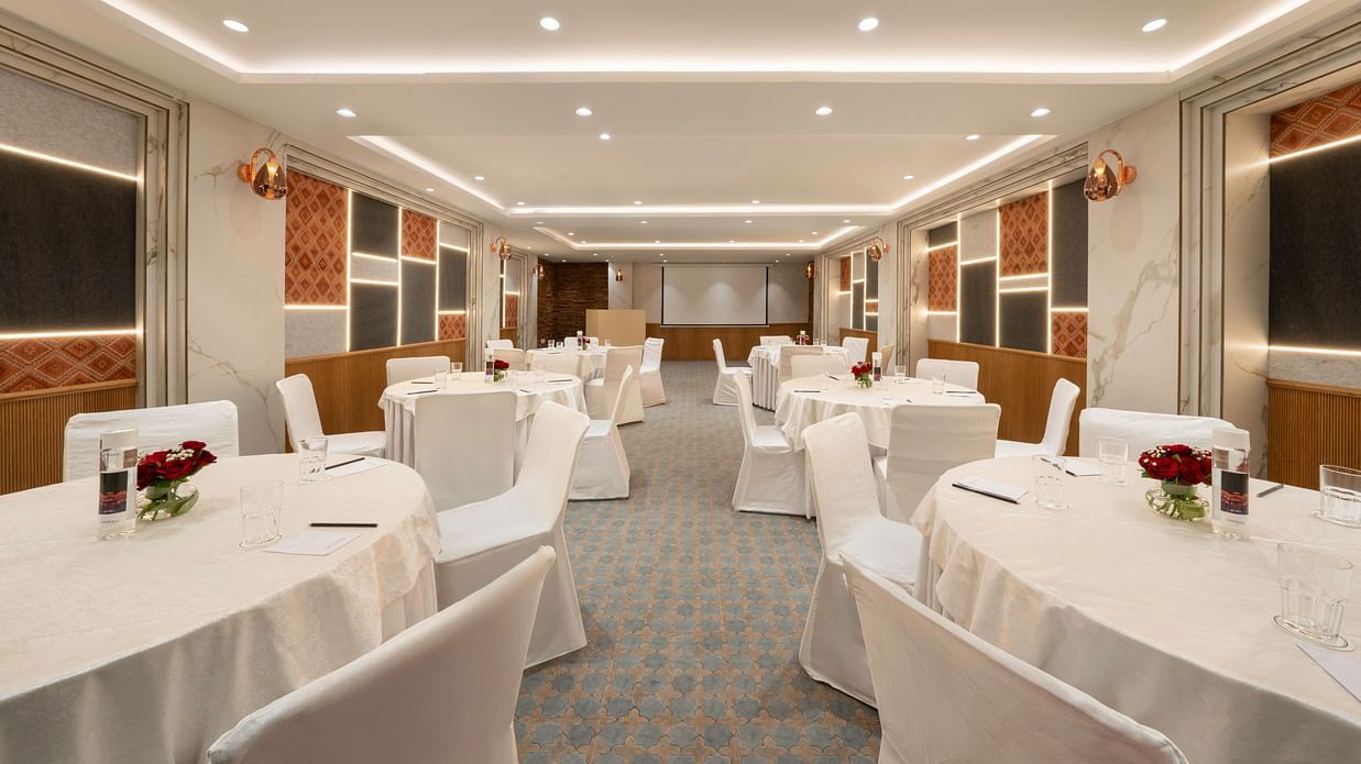 A spacious conference room with round tables and chairs set up for a meeting - Clarks Inn, Indore
