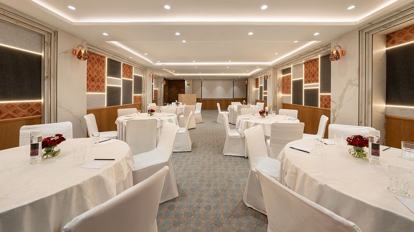 A spacious conference room with round tables and chairs set up for a meeting - Clarks Inn, Indore