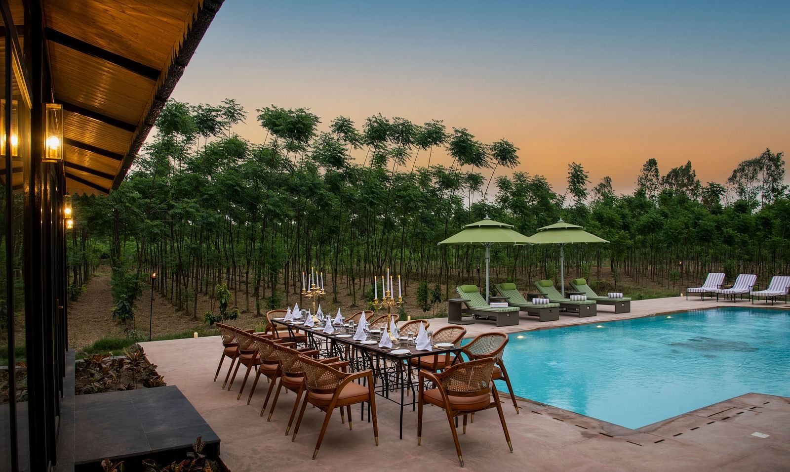 Image of a pool taken in the evening surrounded by trees at Aalia Jungle Resort & Spa - Claridges Collection