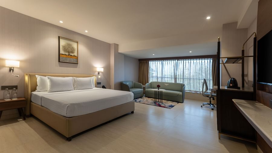  Spacious hotel room with king bed, green sofa, study desk, and large window with curtains at Clarks Inn Suites, Hyderabad
