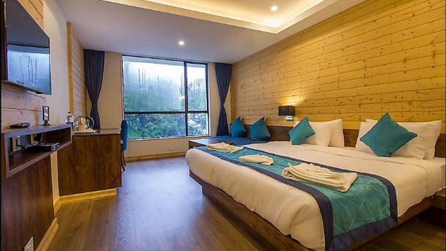 An image of a premium suite with bed, flat screen TV, couch, lamps, an expansive window, and warm lighting - Yashshree Sanderling, Darjeeling