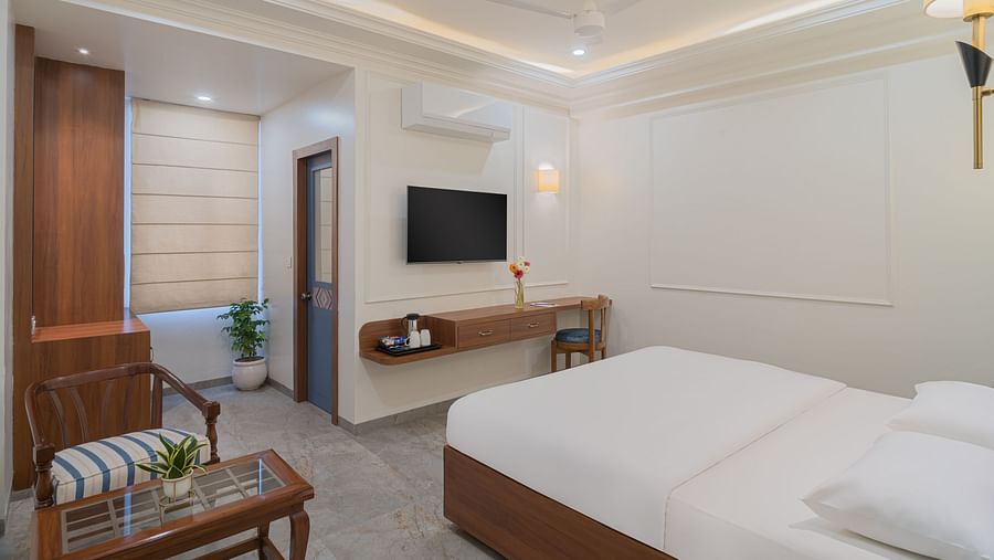 A spacious room with wooden furniture, a wall-mounted television, and bright lighting | Hotel Ganga Maiya