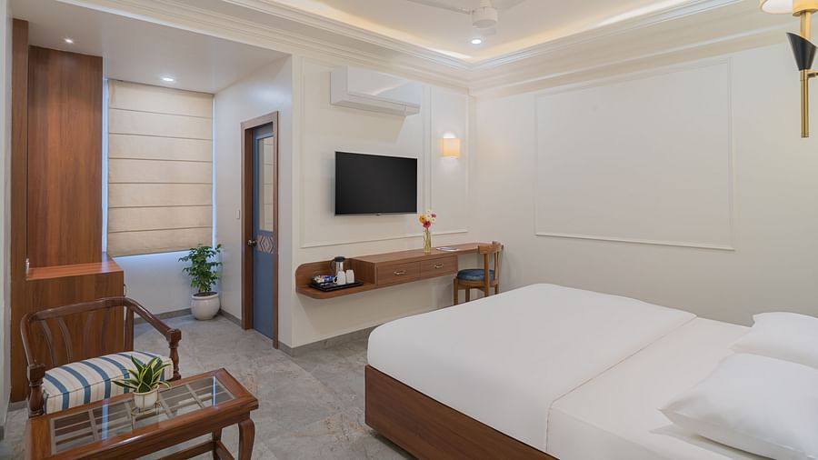 A spacious room with wooden furniture, a wall-mounted television, and bright lighting | Hotel Ganga Maiya