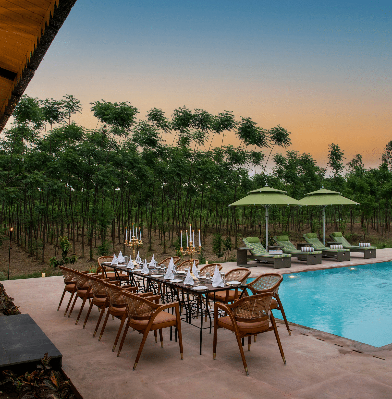 Image of a pool with poolside dining setup surrounded by trees at The Claridges Nabha Residence - Claridges Collection