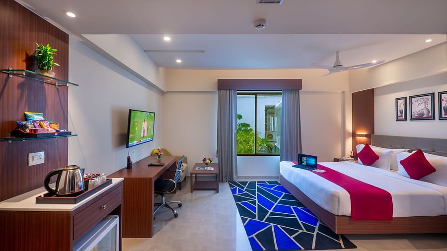 Spacious guest room with bed, seating area, TV and well lit - Lords Eco Inn Shapar Rajkot