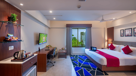 A modern hotel room in Lords Eco Inn Shapar Rajkot with a double bed, TV, and a large window offering an outdoor view