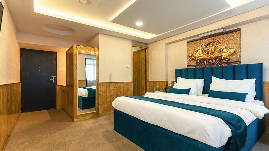 Deluxe Room with a king size bed, inviting ambiance, wooden bedside table at Avianna Seven Seas, Darjeeling.
