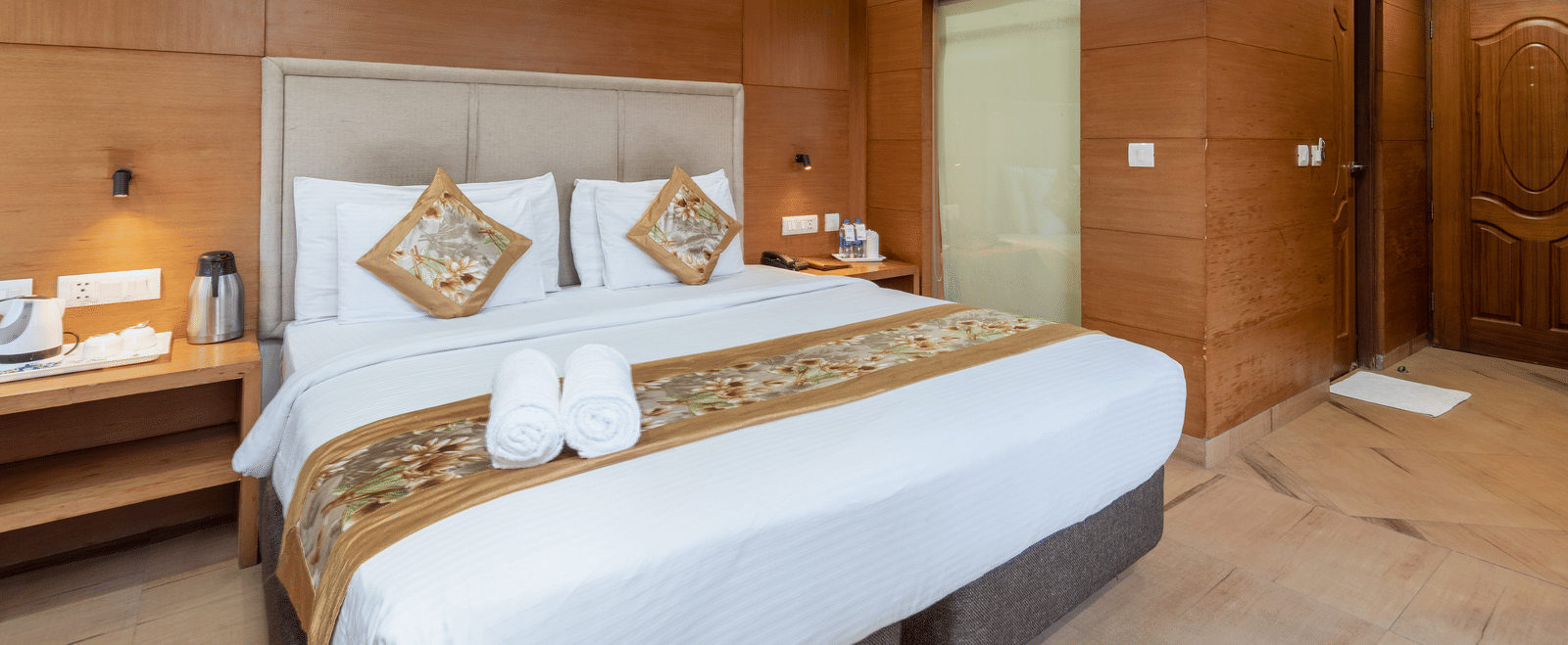 A bedroom featuring a king size bed, and a table with bottled water and a glass at DLS Hotels The Rock Castle.