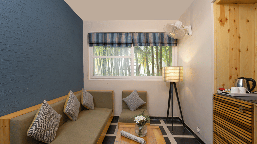 Lounge area featuring a sofa, a wooden  table, and a window with blinds at The Golden Tusk, Jim Corbett