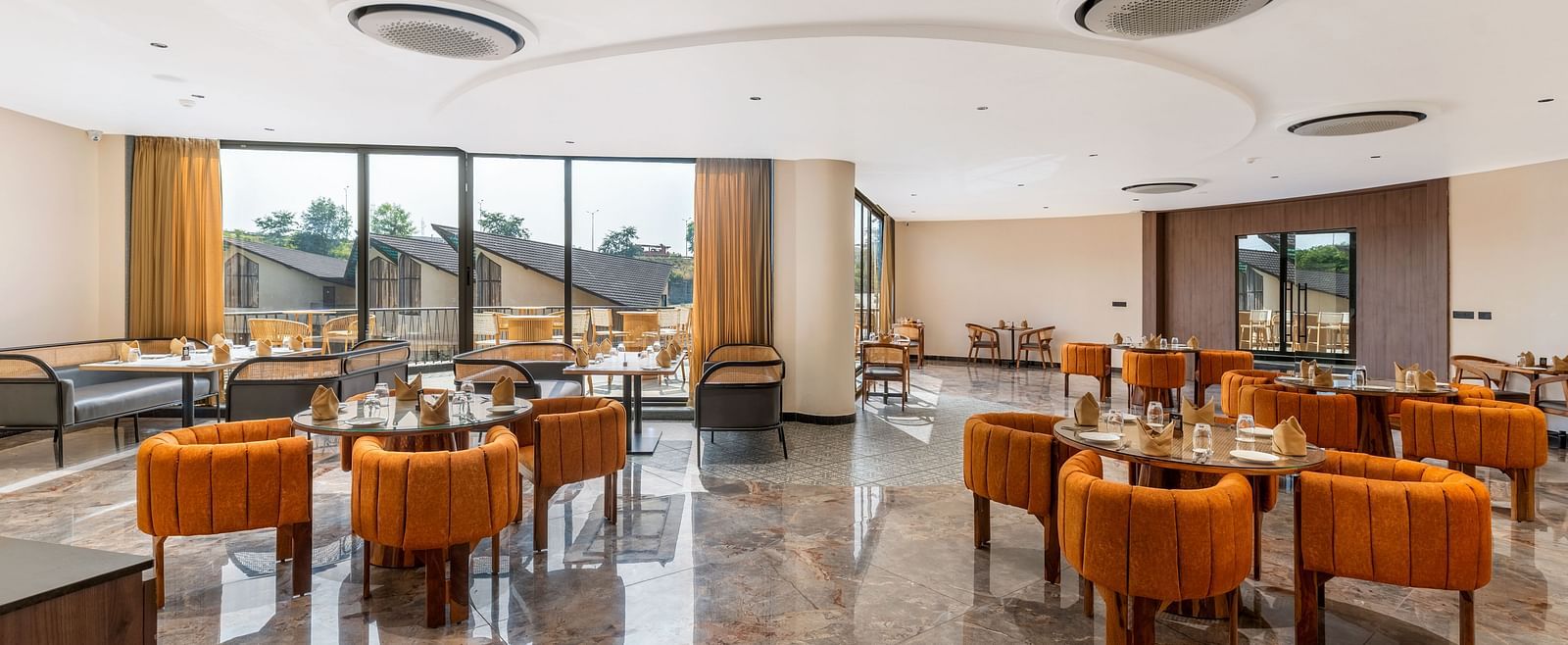 Fine Dine featuring contemporary furniture, warm lighting, and large windows overlooking an outdoor space at The Qualia Resort Club & Brewery, Udaipur.