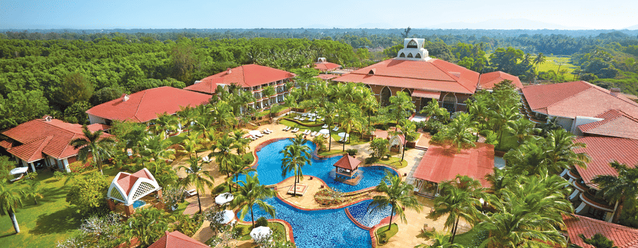aerial view of Caravela Beach Resort Goa with forest cover in the background.