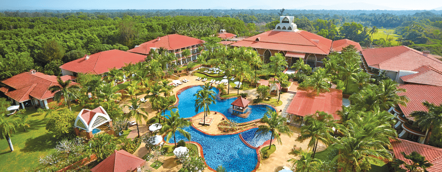 aerial view of Caravela Beach Resort Goa with forest cover in the background.