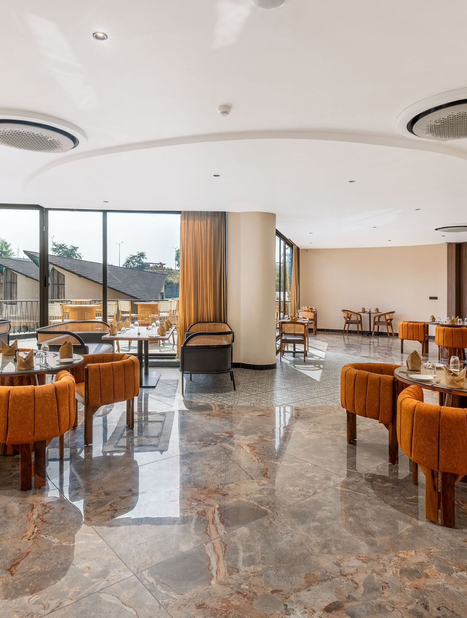 Fine Dine featuring contemporary furniture, warm lighting, and large windows overlooking an outdoor space at The Qualia Resort Club & Brewery, Udaipur.