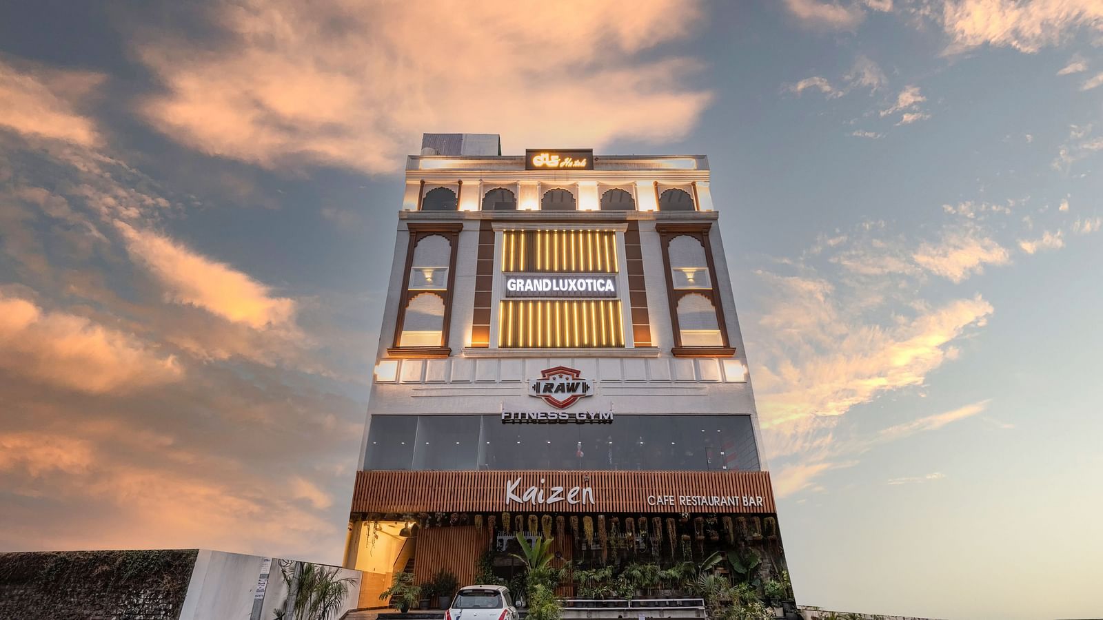 Facade of DLS Grand Luxotica, Dehradun lit up under the vibrant evening sky