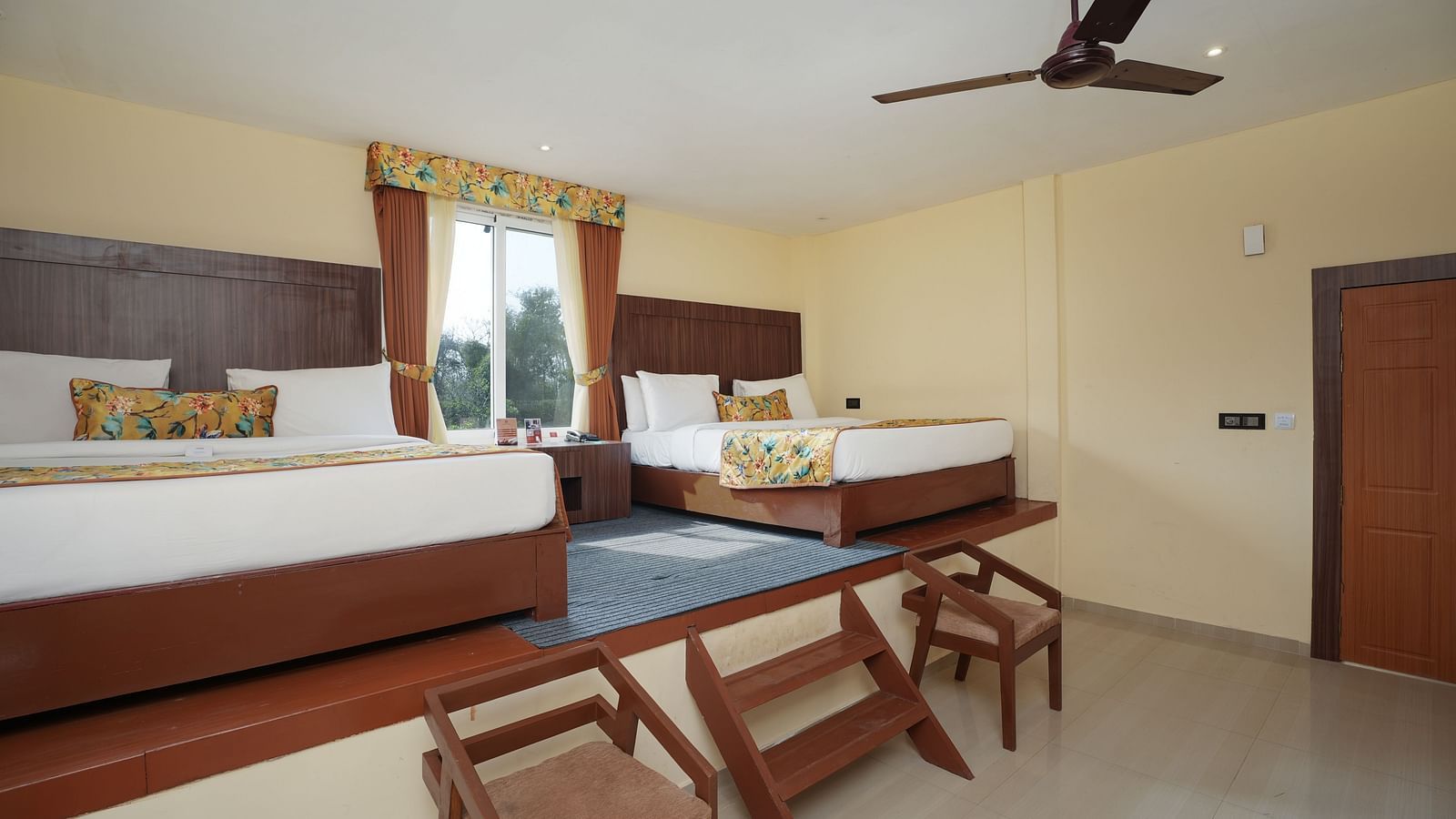 Family room with two large beds with few stairs leading to it at Summit Green Lake Tea Resort & Spa, Kaziranga
