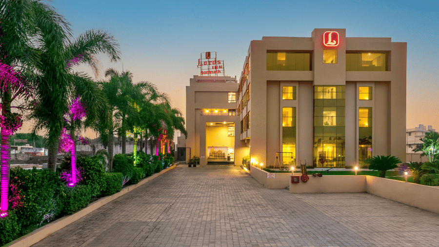 Facade of Lords Inn Somnath at dusk, showcasing its entrance through a beautifully lit driveway.