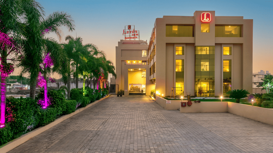 Facade of Lords Inn Somnath at dusk, showcasing its entrance through a beautifully lit driveway.