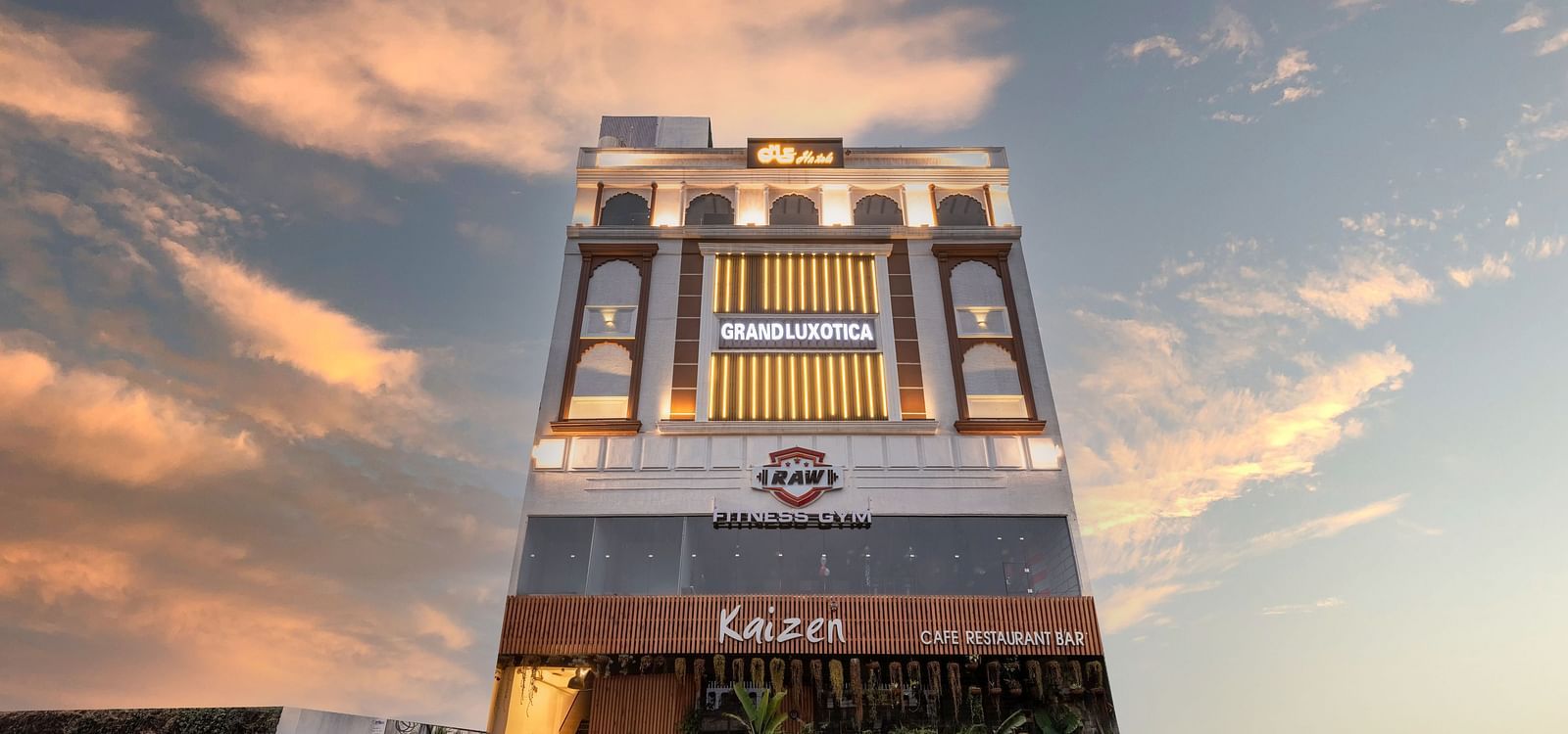 Facade of DLS Grand Luxotica, Dehradun lit up under the vibrant evening sky