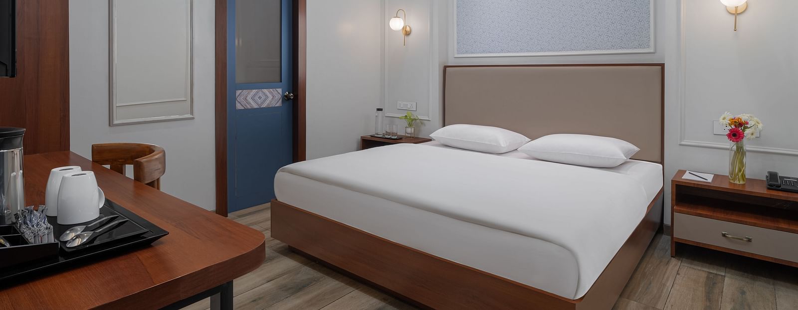 A spacious room with a large bed, wooden bedside tables on both sides, and inviting lighting | Hotel Ganga Maiya