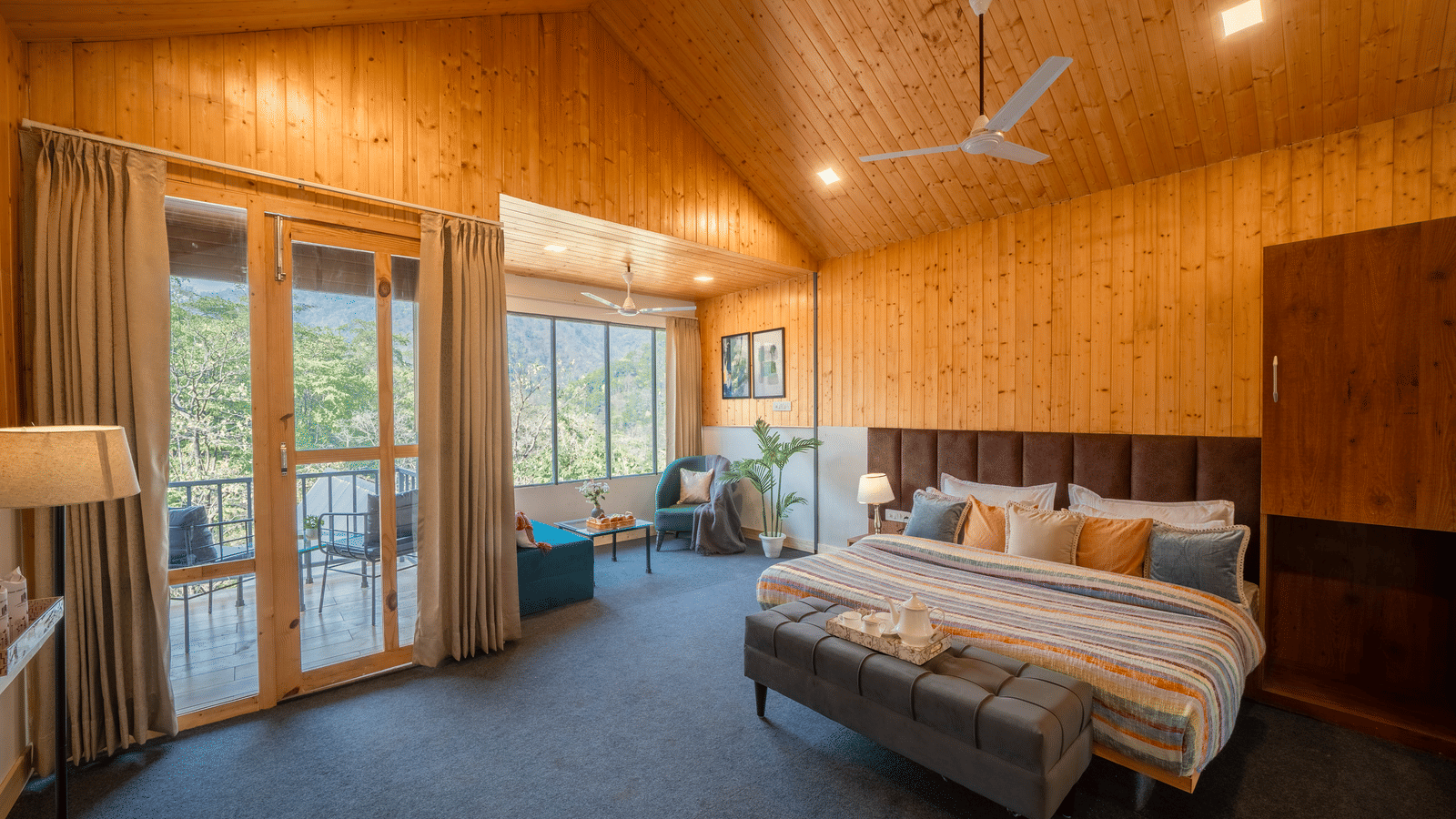 A bedroom at Perfect Stayz The Jungle Resort features a large bed, a window, and a ceiling fan.