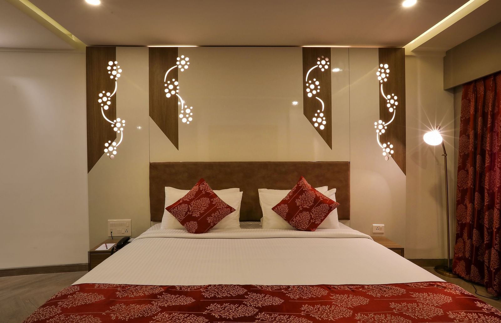 Hotel bedroom with red curtains and decorative wall lights | Mango Hill Central, Chennai