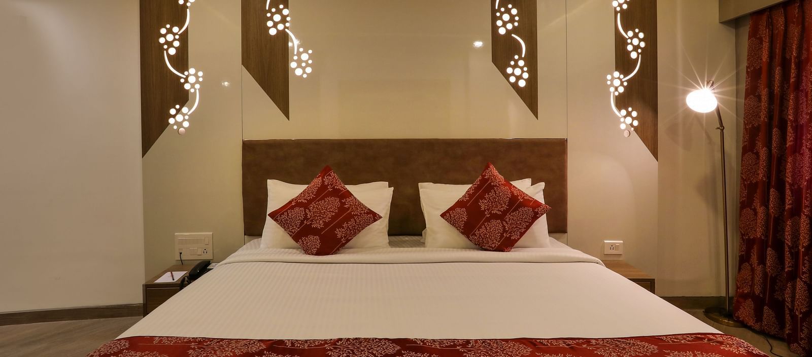 Hotel bedroom with red curtains and decorative wall lights | Mango Hill Central, Chennai