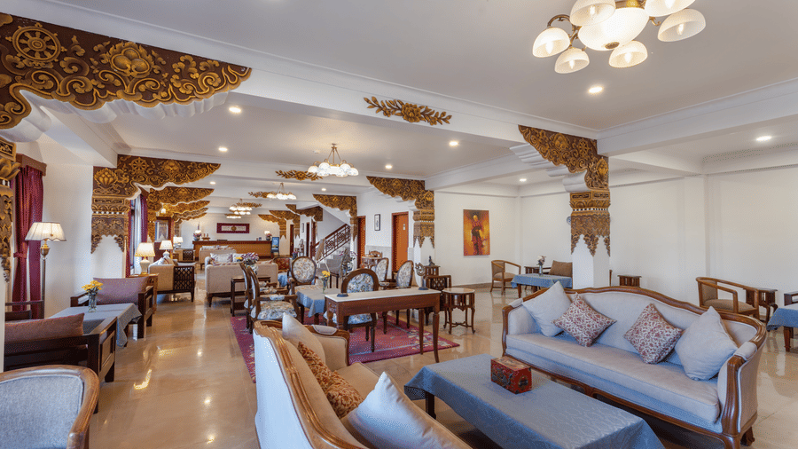 The restaurant interior at Summit Norbu Ghang - The Signature Collection, Gangtok, with multiple sofas, dining tables, chairs, and chandelier lighting.