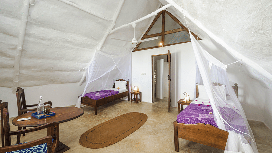 A spacious tented room with decorative bedding, and wooden furniture, featuring two single beds in Sea View Family Cottages - Shooting Star Boutique Hotel