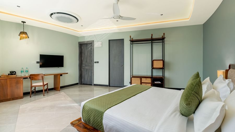Pool View Room featuring a king size bed with green accents, a television, a desk, and a view of the outside at The Qualia Resort Club & Brewery, Udaipur.