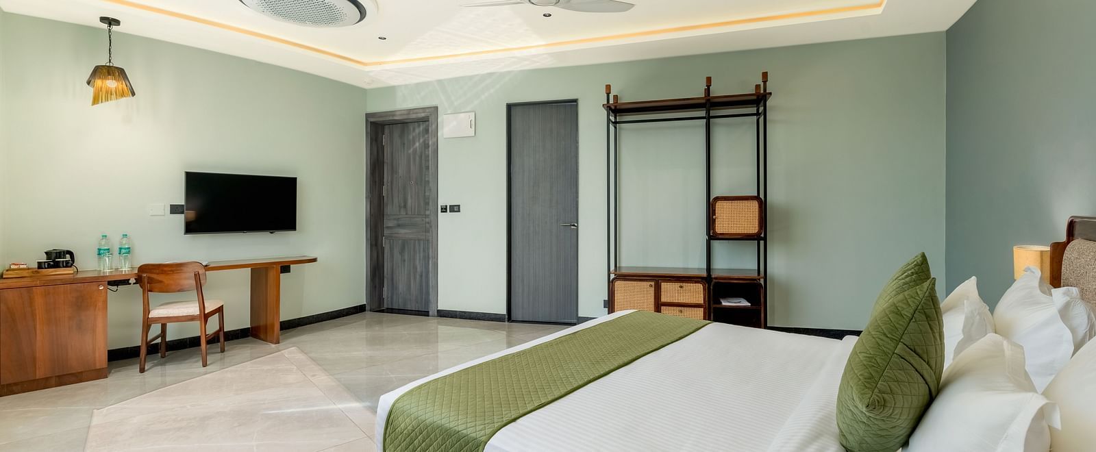 Pool View Room featuring a king size bed with green accents, a television, a desk, and a view of the outside at The Qualia Resort Club & Brewery, Udaipur.