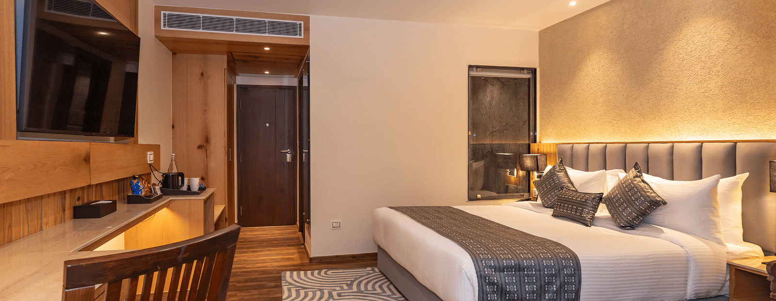 An image of Deluxe Room with a bed, bed side table, flat screen TV, work desk and chair, and a rug - The Belvedere Himalayan Retreat, McLeodganj