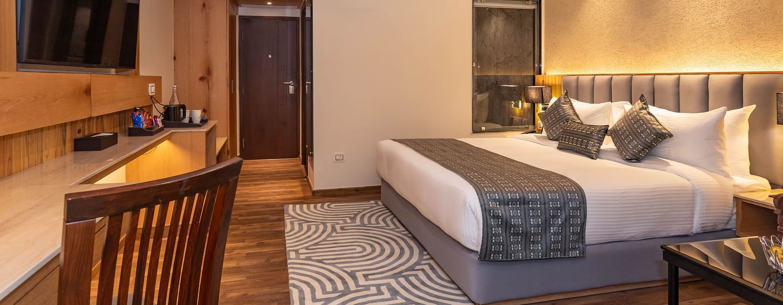 An image of Deluxe Room with a bed, bed side table, flat screen TV, work desk and chair, and a rug - The Belvedere Himalayan Retreat, McLeodganj