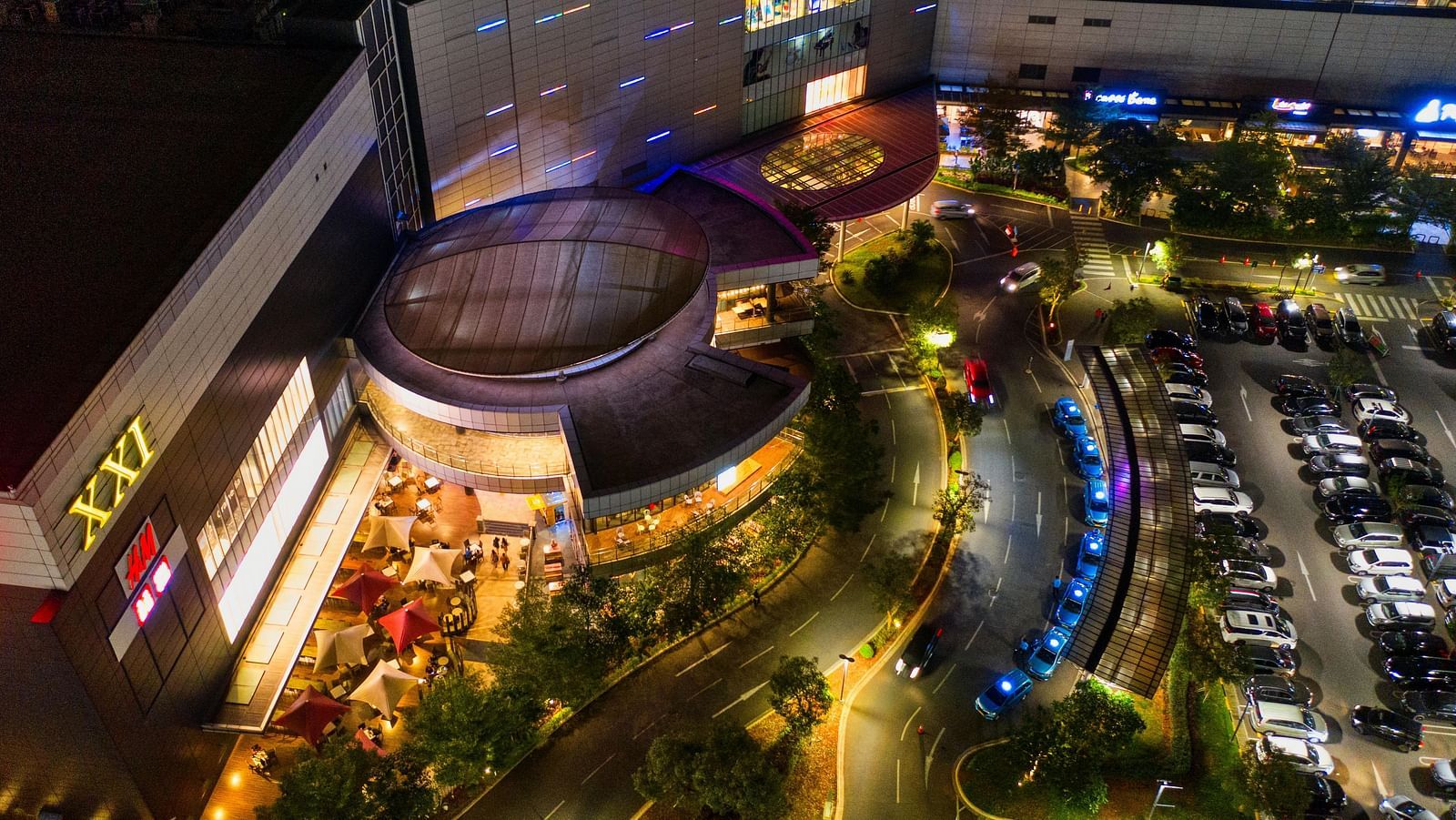 A night image of a wall with numerous vehicles parked at the entrance