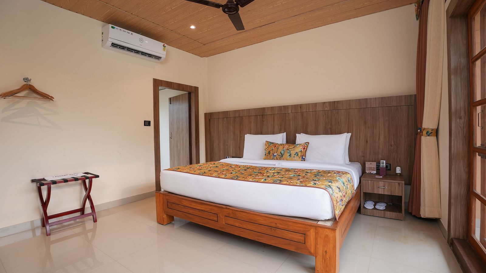 Bungalow featuring a spacious bed with wooden headboards, bedside table, air conditioning at Summit Green Lake Tea Resort & Spa, Kaziranga