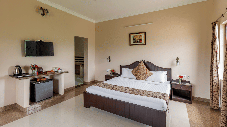 A well-lit guest room with a bed and window alcove seating at Mewar Mansion Villa By Amantra, Udaipur.