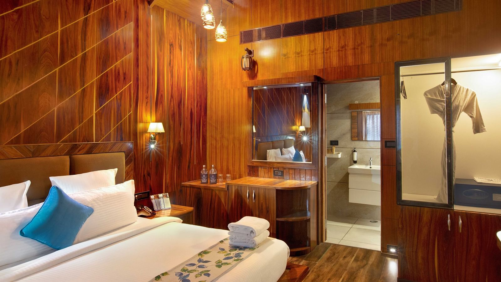 Angular shot of Coral Azure at Coral Reef Resort and Spa in Havelock featuring a double bed in the wooden-furnished room with a mirror next to it mounted on the wall beside which the door to the bathroom opens