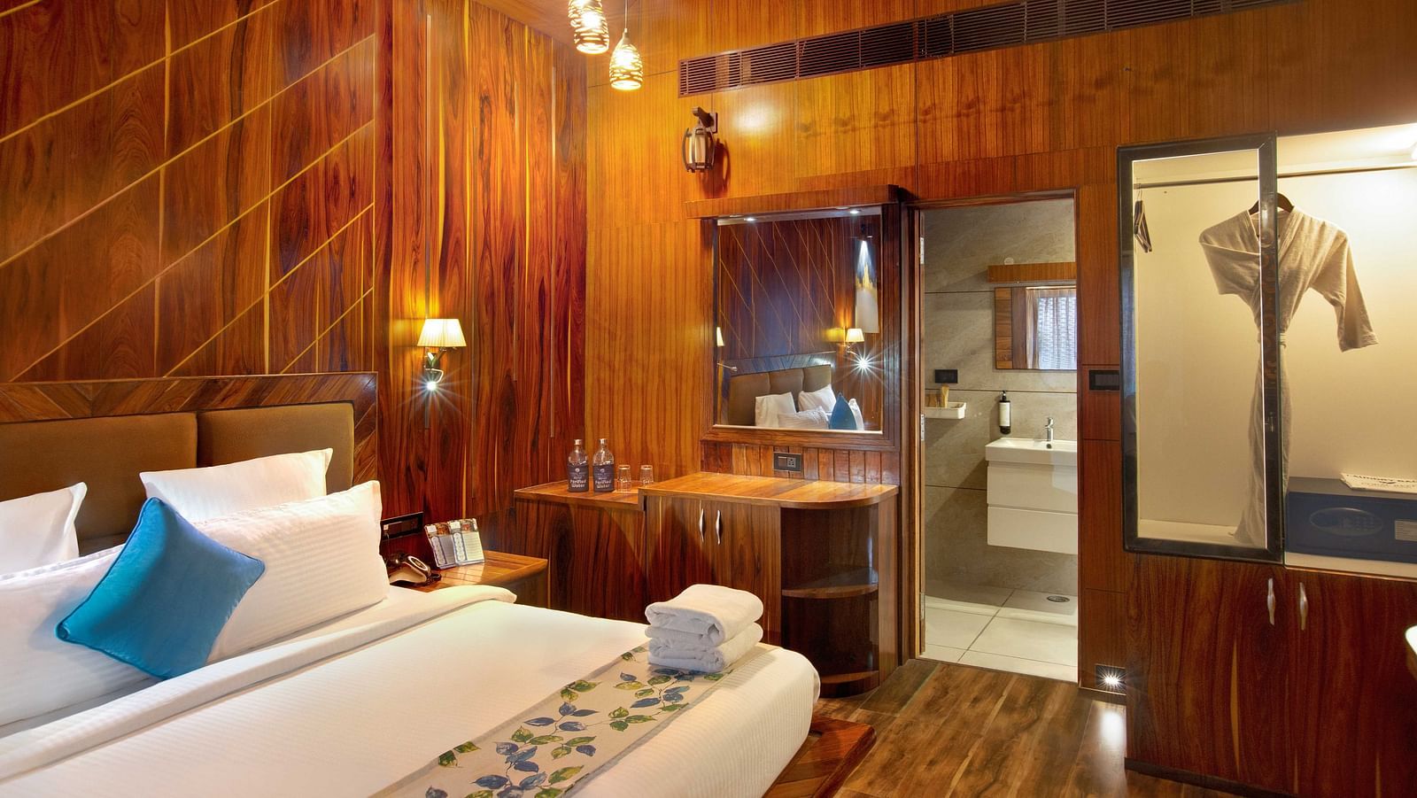 Angular shot of Coral Azure at Coral Reef Resort and Spa in Havelock featuring a double bed in the wooden-furnished room with a mirror next to it mounted on the wall beside which the door to the bathroom opens
