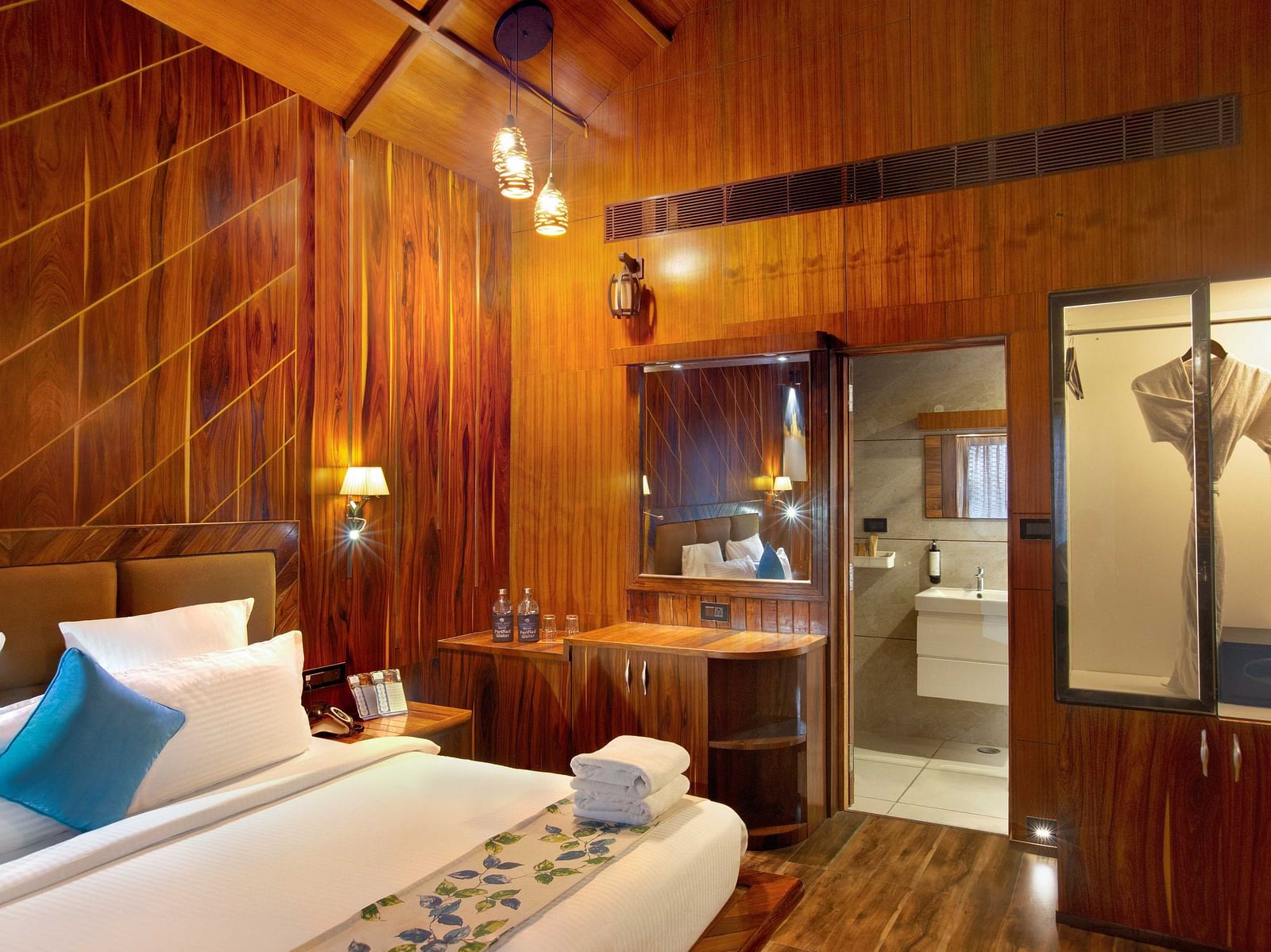 Angular shot of Coral Azure at Coral Reef Resort and Spa in Havelock featuring a double bed in the wooden-furnished room with a mirror next to it mounted on the wall beside which the door to the bathroom opens