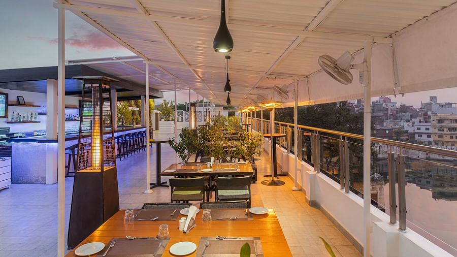 the seating area of the rooftop restaurant  in udaipur with a view of the lake and sky - Hotel Rajdarshan, Udaipur.
