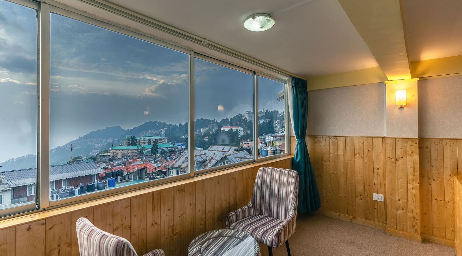 The suite boasts large windows extending along one side of the room and comfortable, cushioned furniture to enjoy the stunning view at Avianna Seven Seas, Darjeeling2
