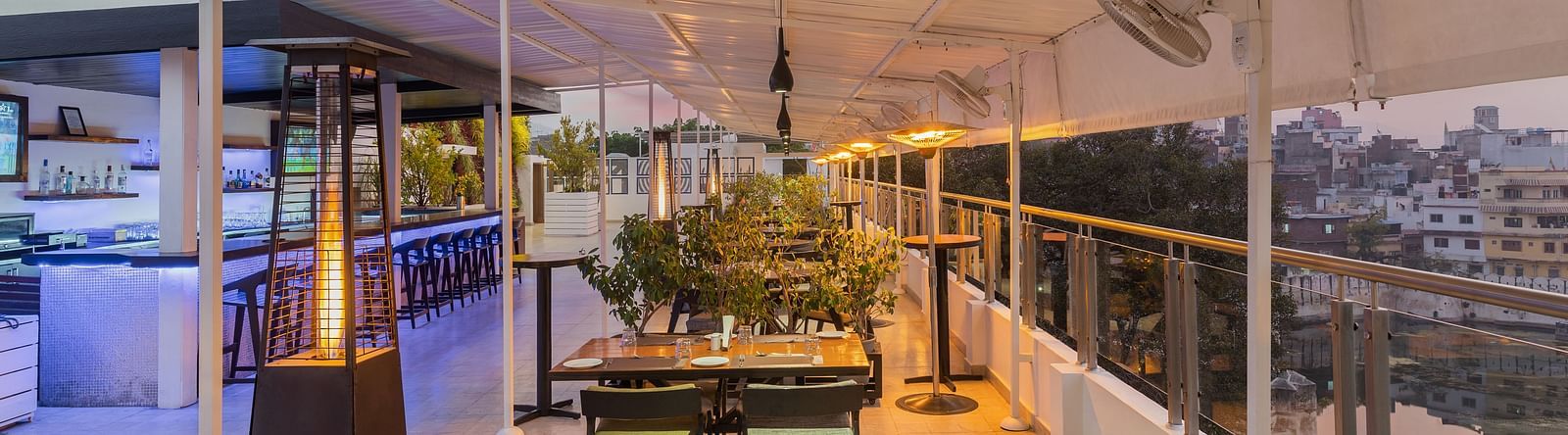 the seating area of the rooftop restaurant  in udaipur with a view of the lake and sky - Hotel Rajdarshan, Udaipur.