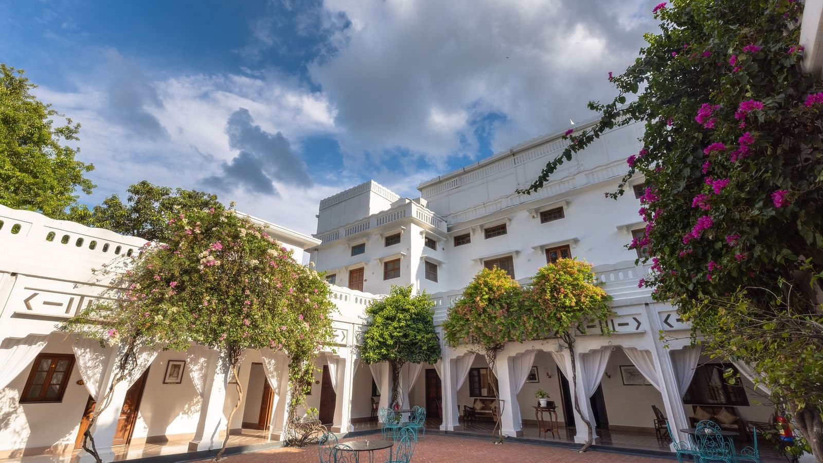 A wide angle view of the courtyard at Saraca Hotel, Lucknow with a teal coloured dining arrangement