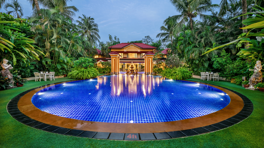 Stunning circular swimming pool lit up at dusk surrounded by palm trees at Mayfair Lagoon
