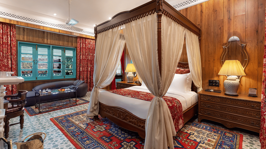 Luxurious suite featuring a classic wooden four-poster bed with drapes at Mayfair Manor, Jungpana.