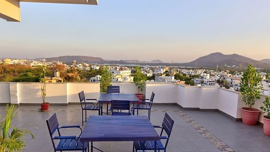 roof top Restaurant with tables and chairs with a hill in the background - - Maan Vilas by Stone Wood, Udaipur
