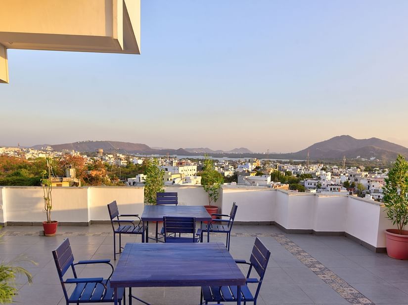 Roof top restaurant with comfortable grey chairs and table and beautiful view of mountains at Maan Vilas by Stonewood 
