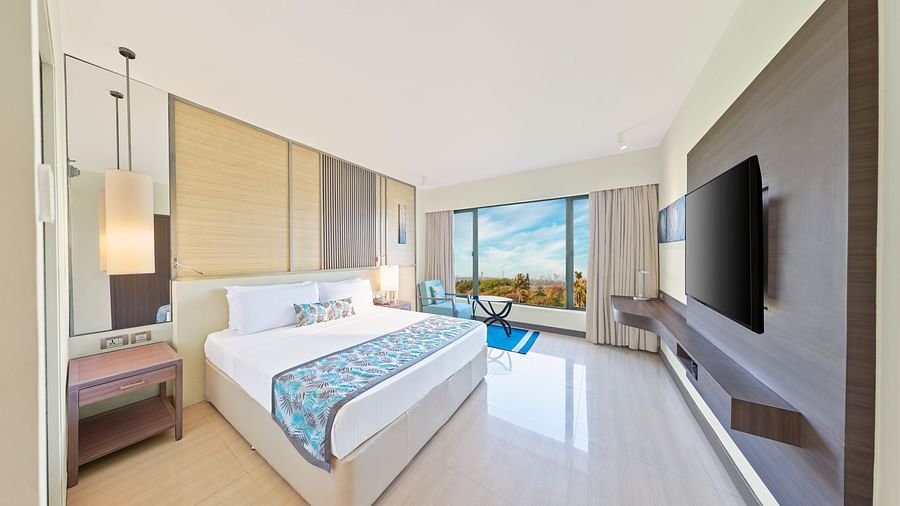 A full view of the bedroom with a bed, mirror on the wall and a huge glass window | The Resort