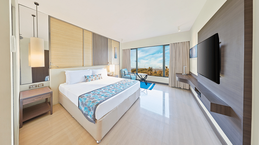 A full view of the bedroom with a bed, mirror on the wall and a huge glass window | The Resort