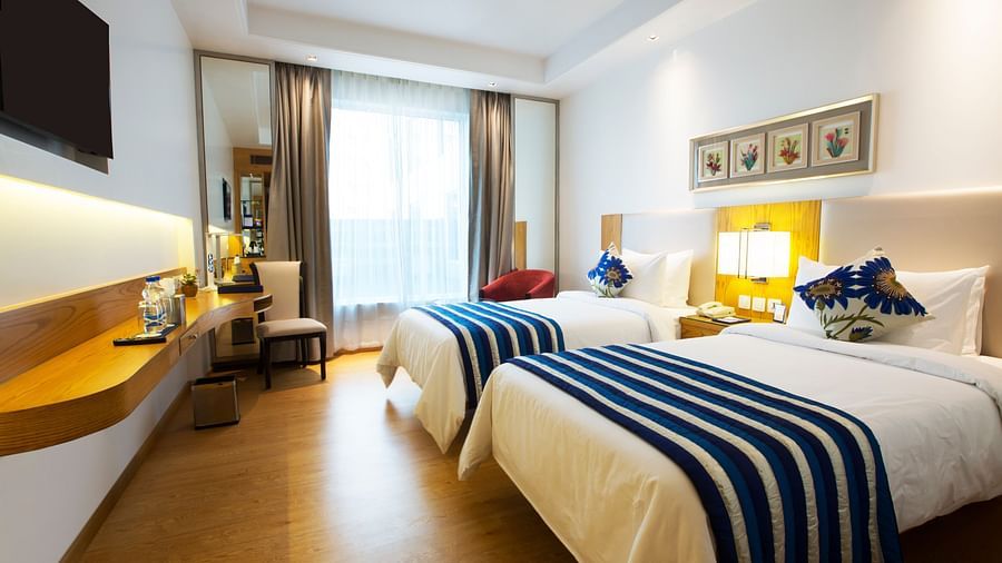 A brightly lit room featuring two single beds with a huge window in the end of the room - Ramada by Wyndham, Ghaziabad, Vasundhara